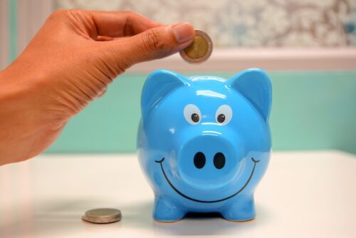 hand dropping coin in piggy bank
