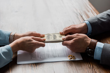 man and woman's hands with money and divorce papers