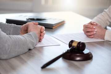two people with hands folded across table and gavel