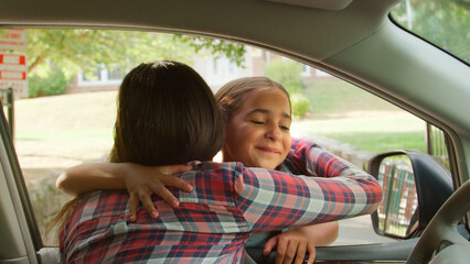 mother and daughter hugging through car window