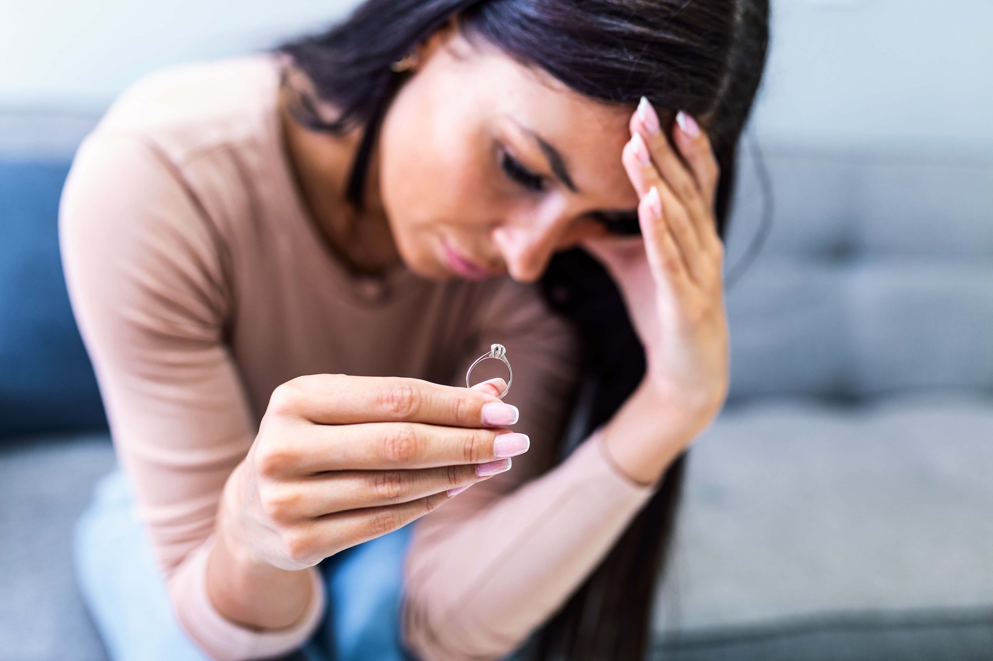 Upset woman holding wedding ring close up cropped image