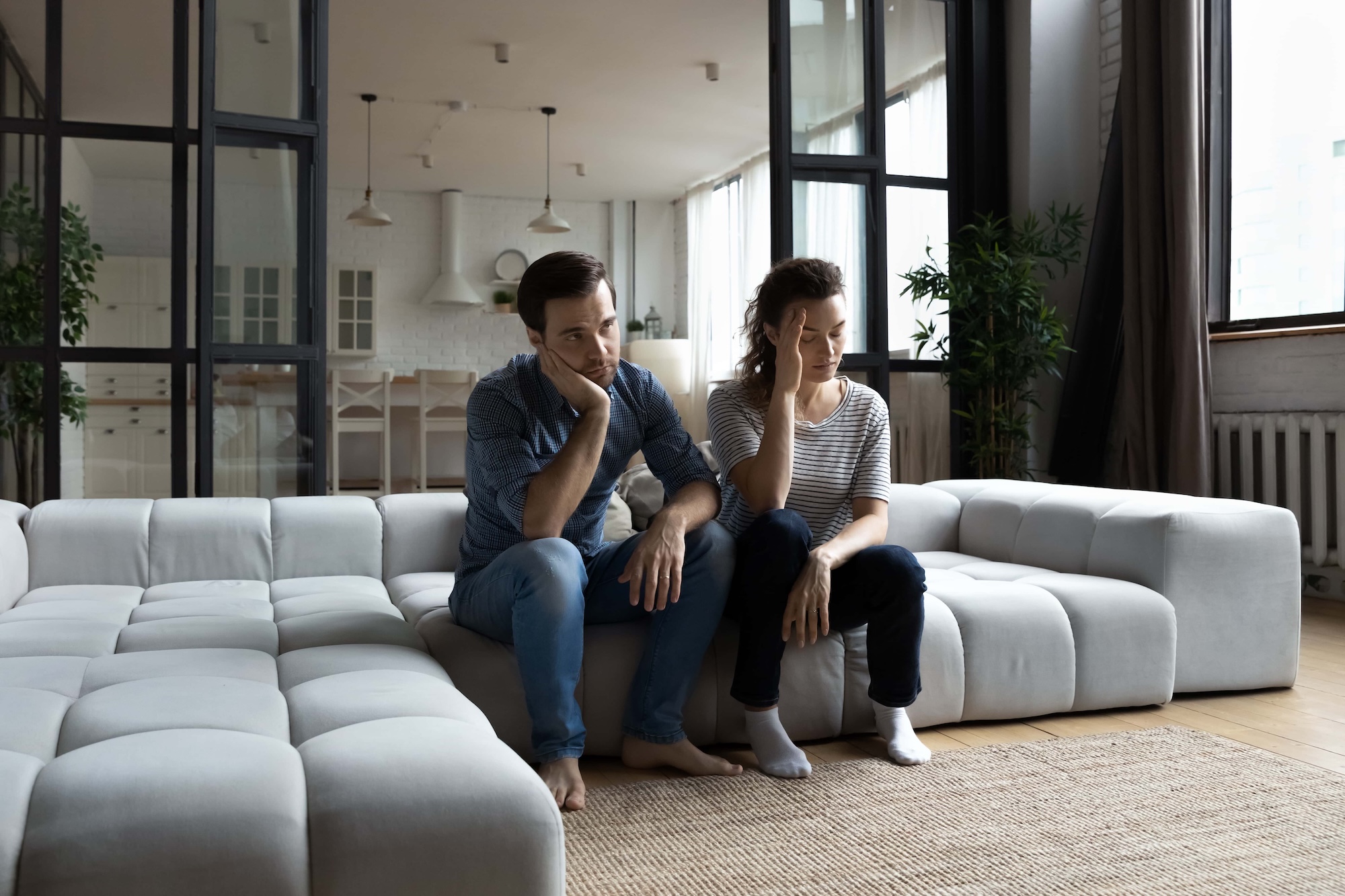 couple sitting on couch together hands on head