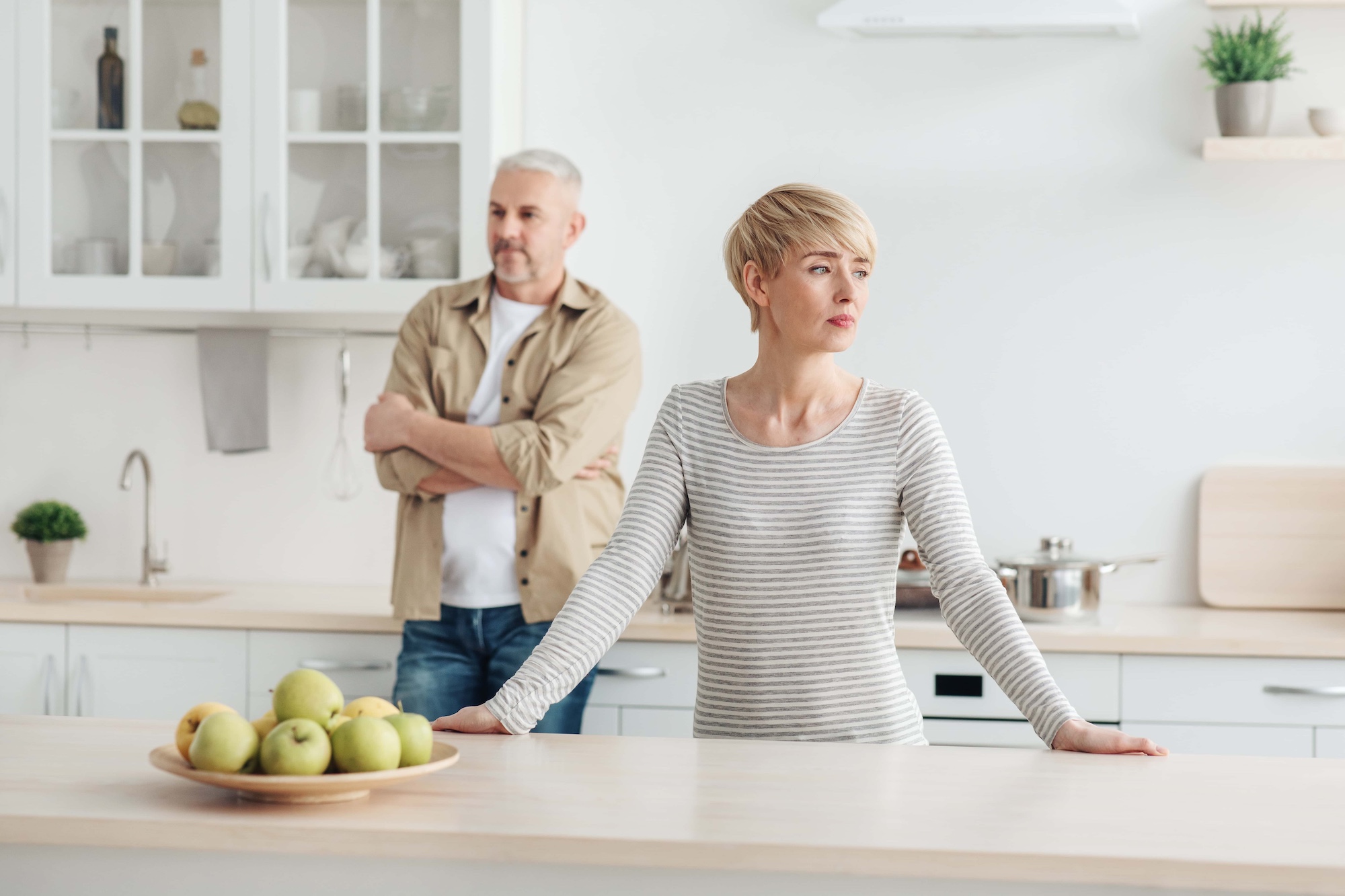 older couple standing in kitchen looking opposite directions