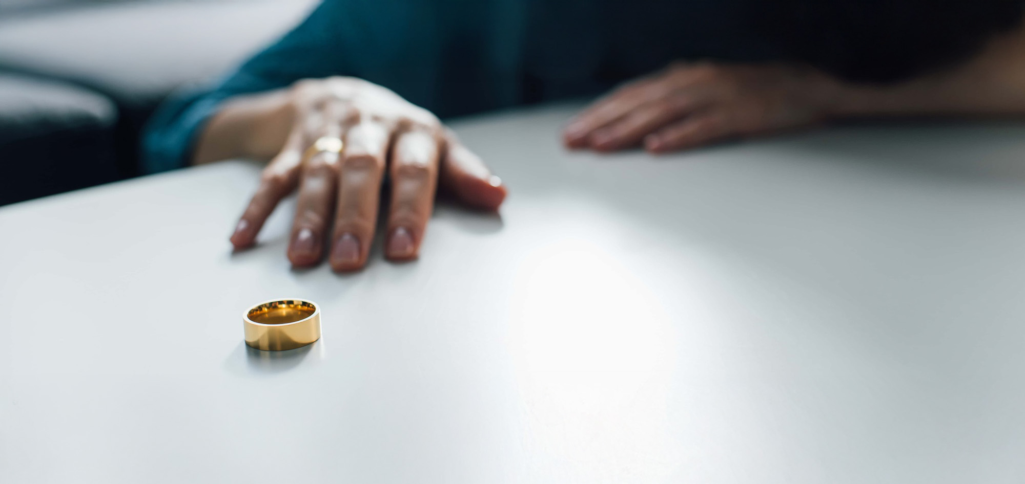 panoramic crop of woman reaching golden ring on coffee table divorce concept