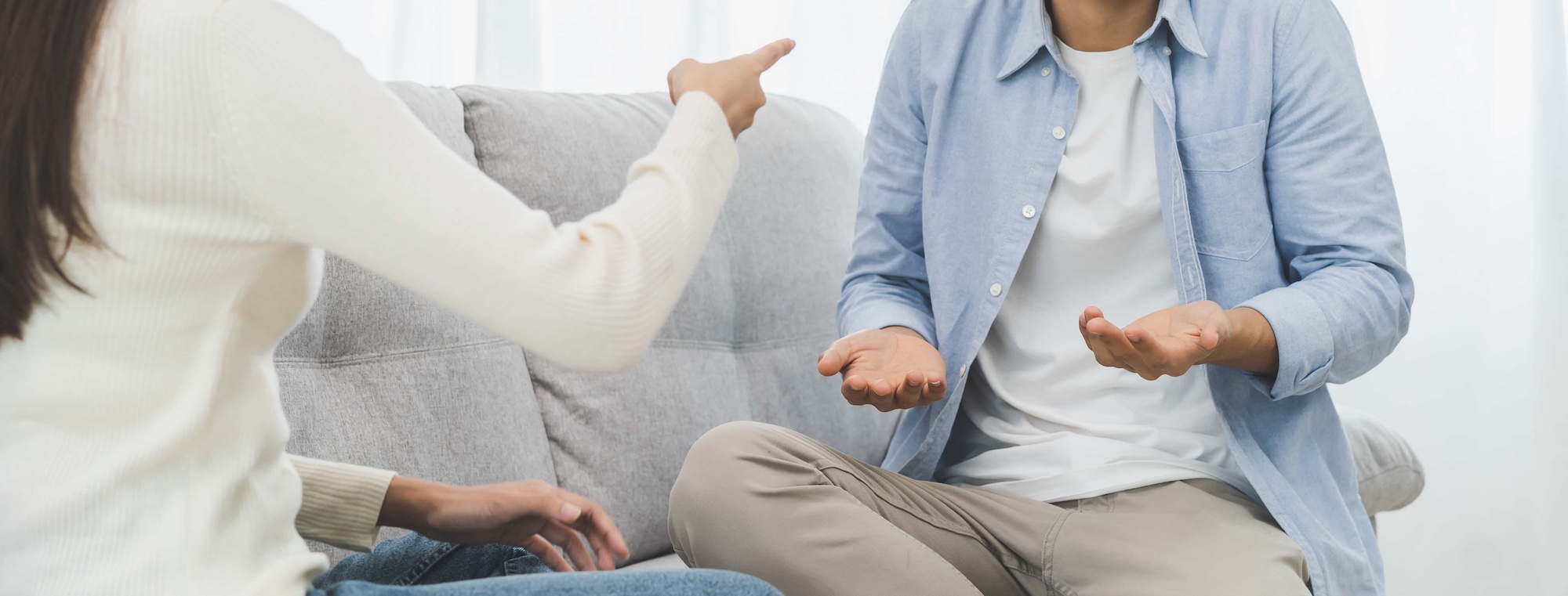two people sitting on couch arguing